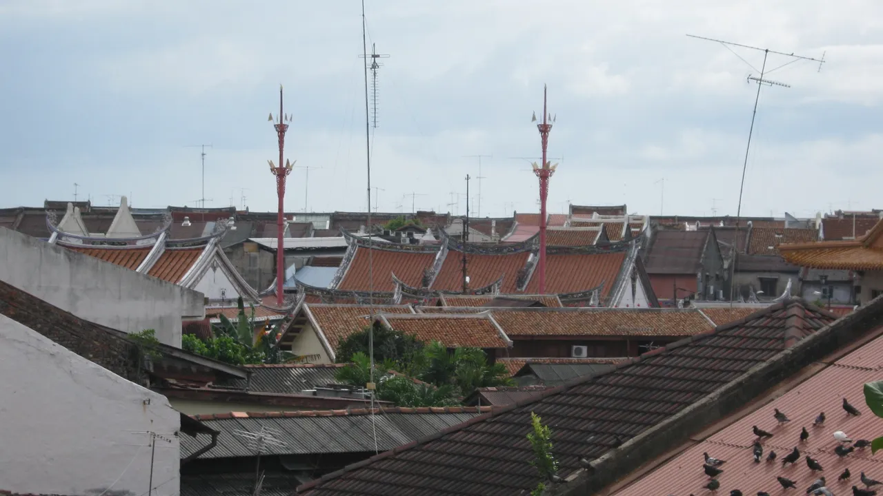 Chinese temple rooftops and swallowtail eaves rising above Melaka's heritage core