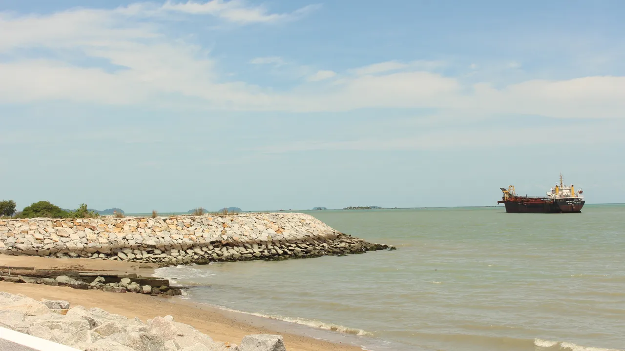 Coastline along the Strait of Malacca near Melaka, with calm water meeting a sandy shore