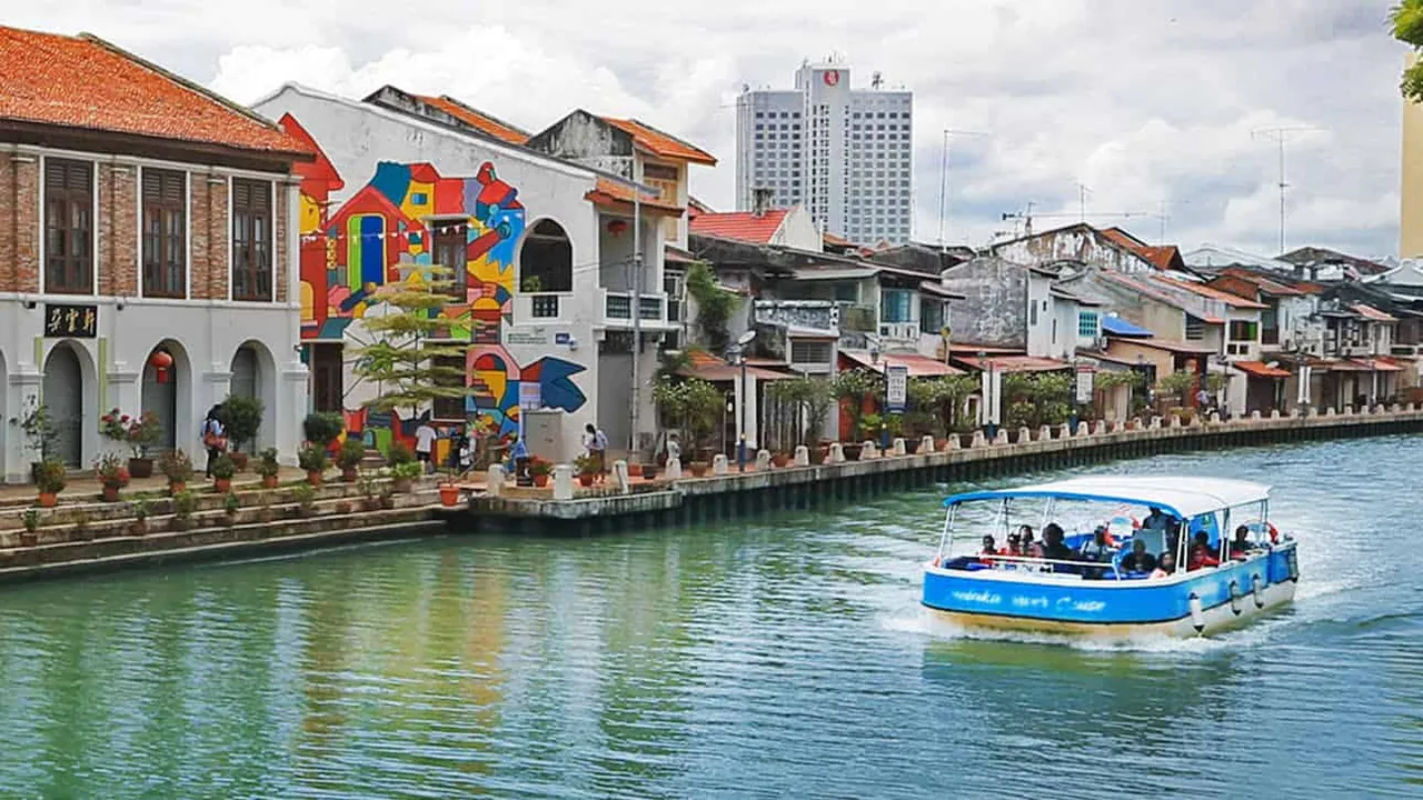 A Melaka River Cruise boat passing riverside shophouses