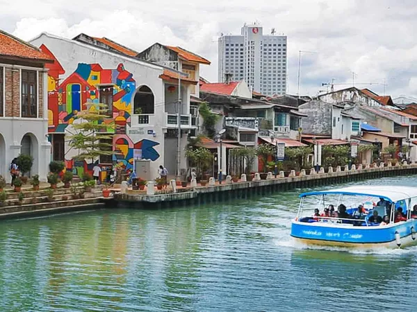 A Melaka River Cruise boat passing riverside shophouses